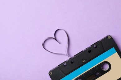Top view of music cassette and heart made with tape on violet background, space for text. Listening love song