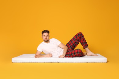 Photo of Man lying on soft mattress against orange background