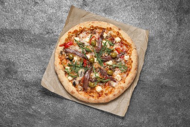 Photo of Tasty pizza with anchovies, arugula and olives on grey table, top view