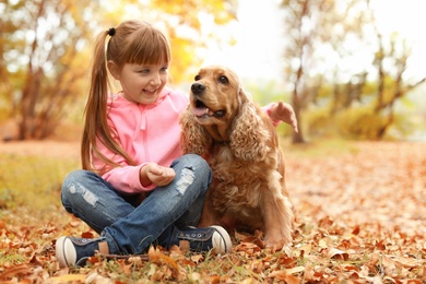 Cute little girl with her pet in park. Autumn walk