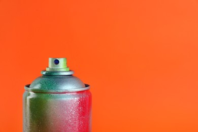 Used can of spray paint on orange background, closeup. Space for text