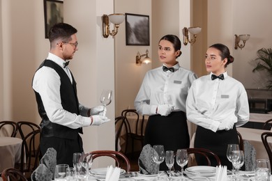Photo of People setting table during professional butler courses in restaurant