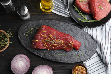 Flat lay composition with fresh beef cut on black wooden table