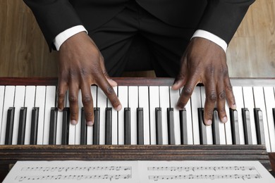 African-American man playing piano indoors, above view. Talented musician