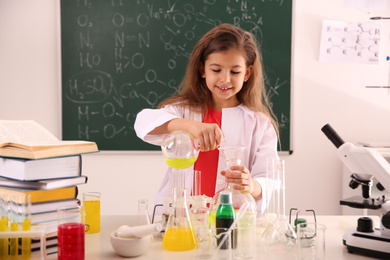 Schoolchild making experiment at table in chemistry class
