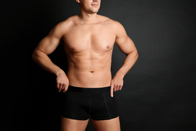 Man with sexy body on black background, closeup. Space for text