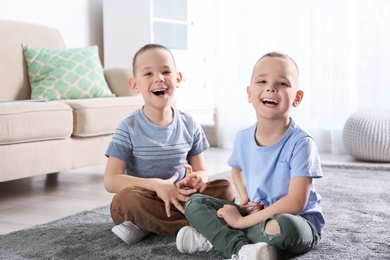 Portrait of cute twin brothers sitting on floor in living room