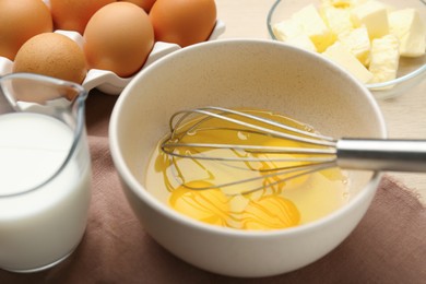 Whisking eggs in bowl on table, closeup