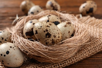 Nest and quail eggs on wooden table, closeup