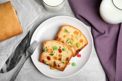 Delicious cake with candied fruits and milk on light grey table, flat lay