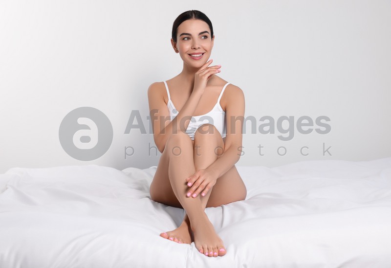 Photo of Young woman showing smooth skin after epilation on bed