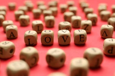 Mini cubes with letters forming word Love on red background, closeup