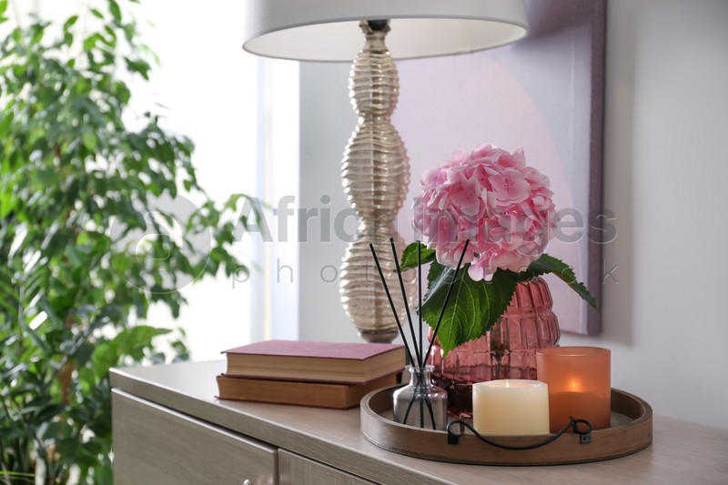 Stylish tray with different interior elements and lamp on chest of drawers indoors