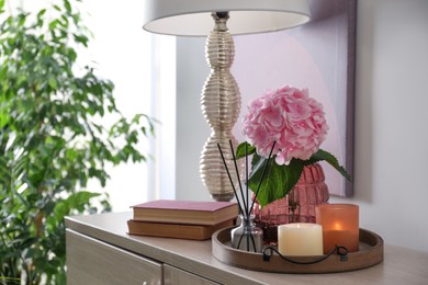 Stylish tray with different interior elements and lamp on chest of drawers indoors