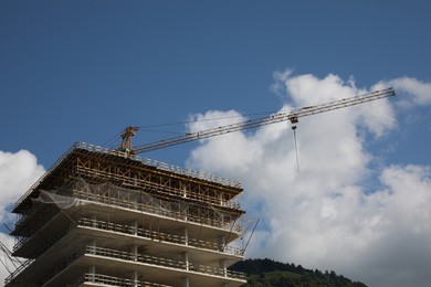 Construction site with tower crane on unfinished building under blue cloudy sky