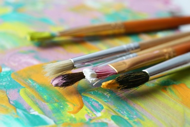 Set of different brushes on abstract colorful paint, closeup