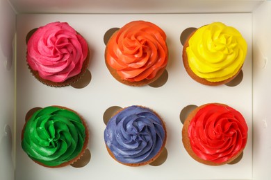 Many delicious colorful cupcakes in box, top view