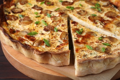 Delicious pie with mushrooms and cheese on wooden serving board, closeup