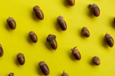 Photo of Many acorns on yellow background, flat lay
