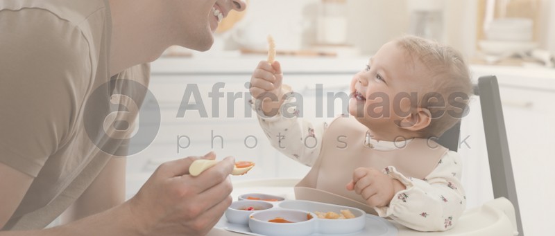 Father feeding his cute little baby healthy food at home. Banner design