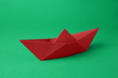 Photo of Origami art. Red paper boat on green background
