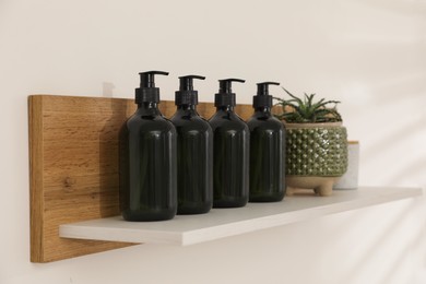 Bottles of hygiene products and houseplant on shelf in bathroom