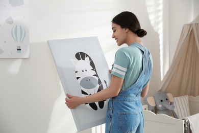 Photo of Decorator with picture near white wall. Children's room interior design