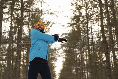 Man doing sports exercises in winter forest, low angle view