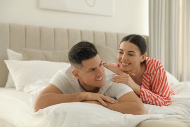 Photo of Happy couple in pyjamas lying on bed at home