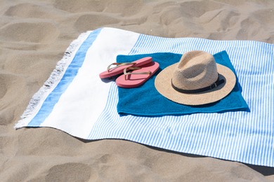 BLue towels, flip flops and straw hat on sandy beach