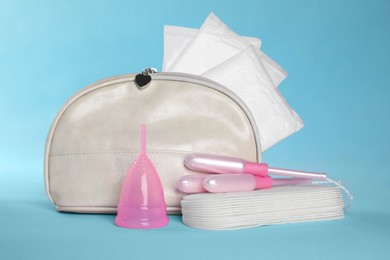 Bag with menstrual pads and other hygiene products on light blue background