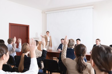 Photo of People raising hands to ask questions at business conference in meeting room