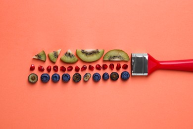 Creative flat lay composition with paint brush, fruits and berries on coral background