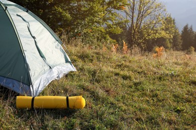 Photo of Sleeping mat near camping tent outdoors. Tourism equipment