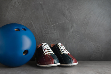 Bowling shoes and ball on grey stone table. Space for text