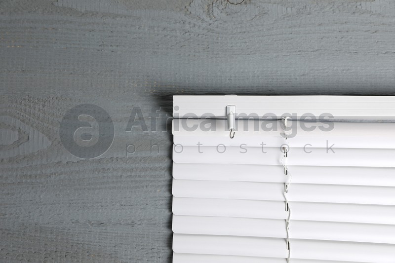Photo of Stylish horizontal window blinds on grey wooden table, top view. Space for text