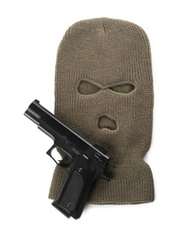 Photo of Beige knitted balaclava and pistol on white background, top view