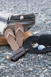 Set of different stylish beach accessories on pebble seashore