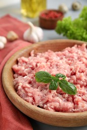 Raw chicken minced meat with basil on table, closeup