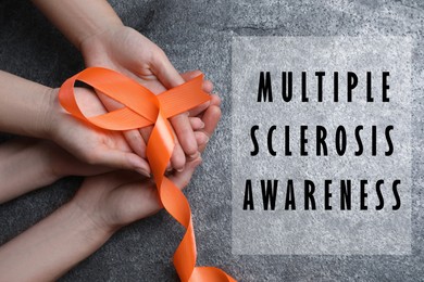 Multiple Sclerosis Awareness Day. People with orange ribbon on grey background, top view