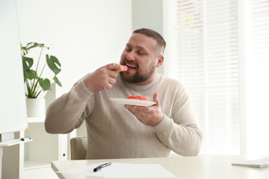 Lazy overweight office employee with donuts at workplace