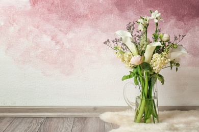 Vase with bouquet of beautiful flowers on floor