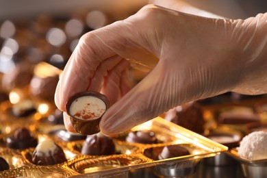 Woman packing delicious candies at production line, closeup