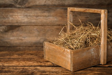 Dried hay in crate on wooden table. Space for text