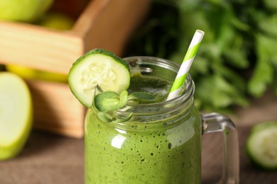 Fresh green smoothie and ingredients on wooden table, closeup