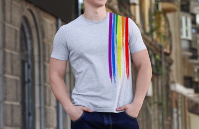 Young man wearing t-shirt with image of LGBT pride flag outdoors