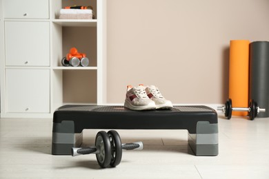 Step platform, sneakers and abdominal wheel indoors. Sports equipment