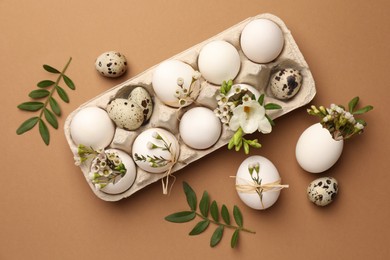 Photo of Festive composition with eggs and floral decor on brown background, flat lay. Happy Easter