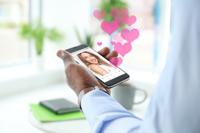 African-American man visiting dating site via smartphone indoors, closeup