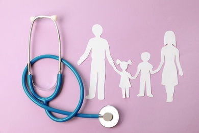 Stethoscope and paper cutout of family on color background, top view